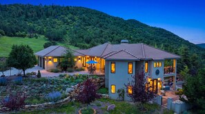 A two-story house with a patio and a view of a forested hill. - Cougar Cañon Ranch, Colorado Mountain Retreat - Incredible Views and Amenities (Cañon City)