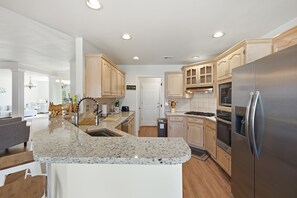 A modern kitchen with granite countertops, stainless steel appliances, and wooden cabinetry.