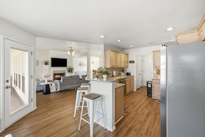 A modern kitchen with wooden cabinets, a stainless steel refrigerator, and a bar area with stools.
