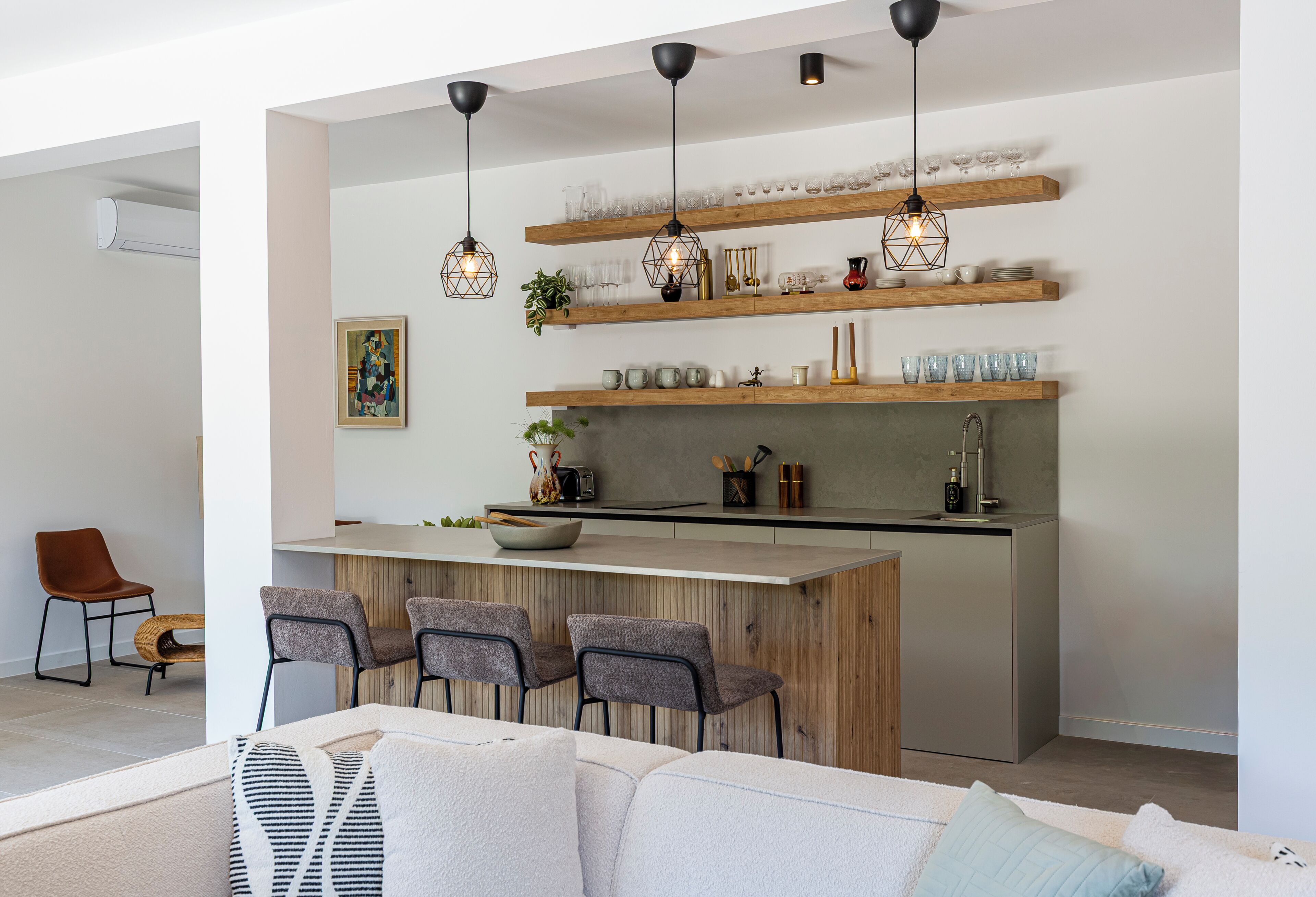 A modern kitchen with wooden shelves, hanging pendant lights, and a bar area.