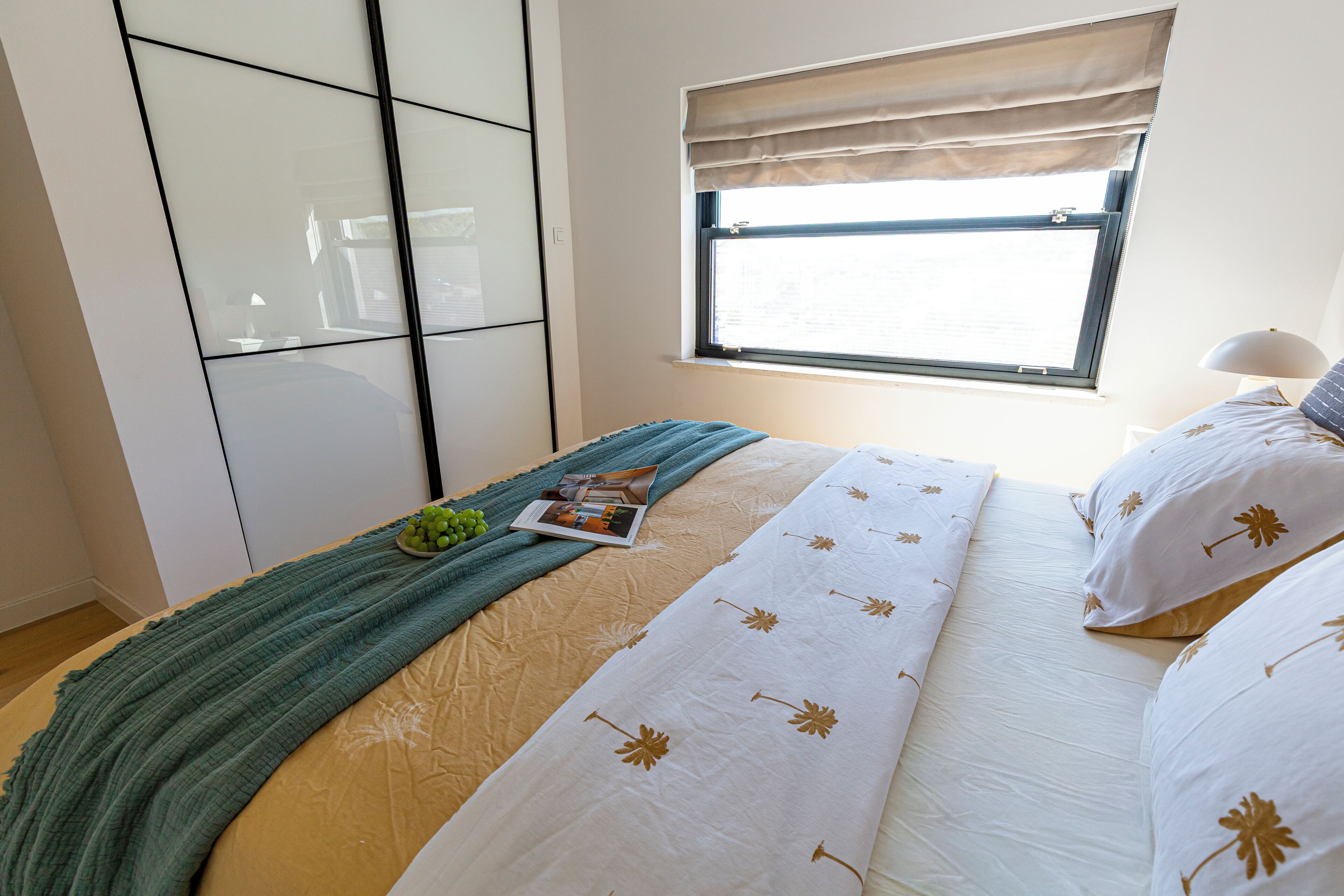 Une chambre à coucher avec un lit, une fenêtre, une table de chevet et une lampe.