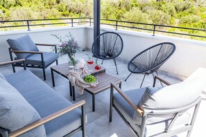 Ein Balkon mit Sitzgelegenheit, einem Tisch und einem Blumenstrauß.