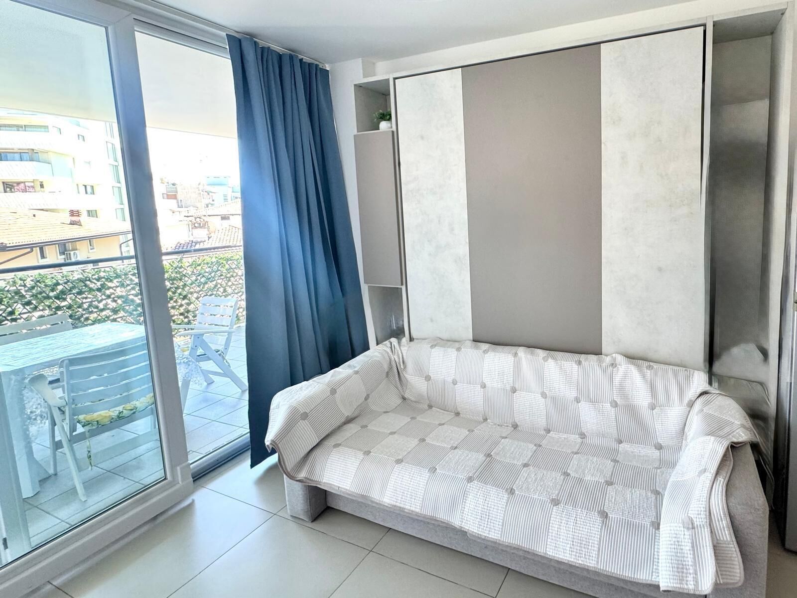 Un salon moderne avec un canapé, une porte-fenêtre coulissante et une vue sur l’extérieur.