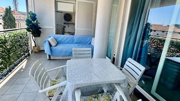 Un balcon avec une table et des chaises, un canapé bleu et une plante en pot.
