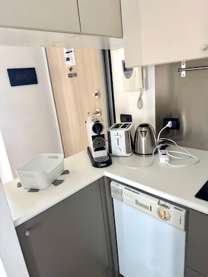 Eine kleine Küchenzeile mit Kaffeemaschine, Toaster, Wasserkocher und Geschirrspüler.