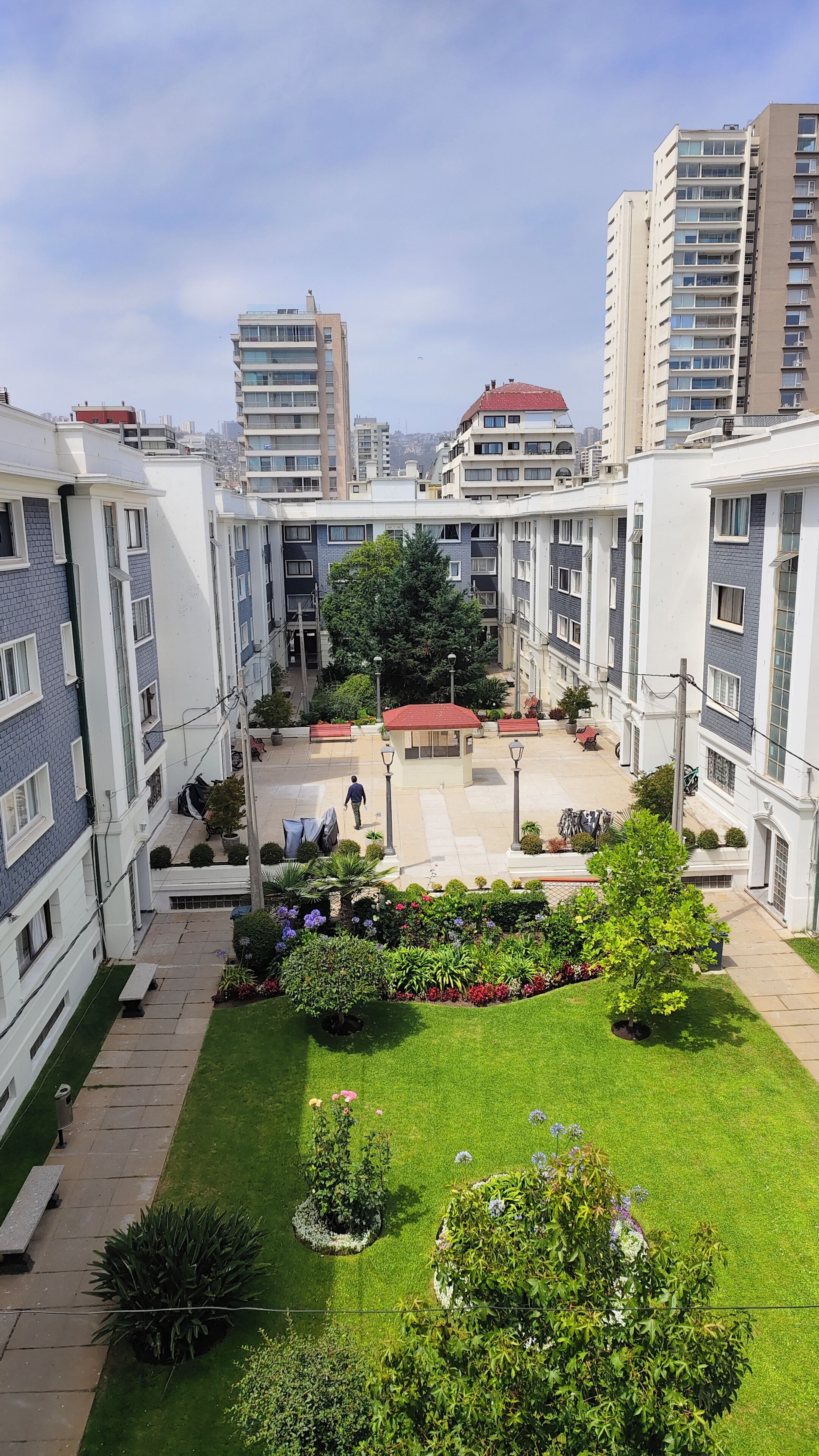 Une cour intérieure avec un espace central aménagé en salon, entourée d’immeubles résidentiels à plusieurs étages.