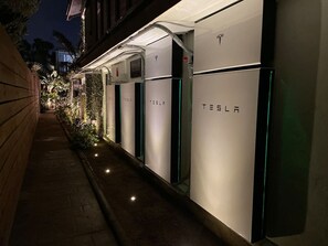 Une rangée de bornes de recharge Tesla le long d’un trottoir, de nuit.