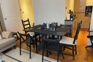 En matplats med ett bord och stolar, ett kök i bakgrunden och en soffa i förgrunden.