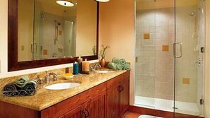 Une salle de bain avec un grand miroir, deux lavabos, une douche et des meubles en bois.