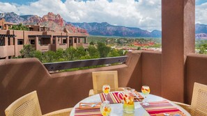Une terrasse avec une table dressée pour le dîner, offrant une vue sur un paysage montagneux.