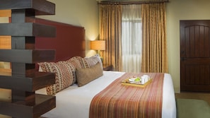 Une chambre d’hôtel avec un lit, des oreillers, un plateau avec des articles pour le petit-déjeuner, une lampe et des rideaux.