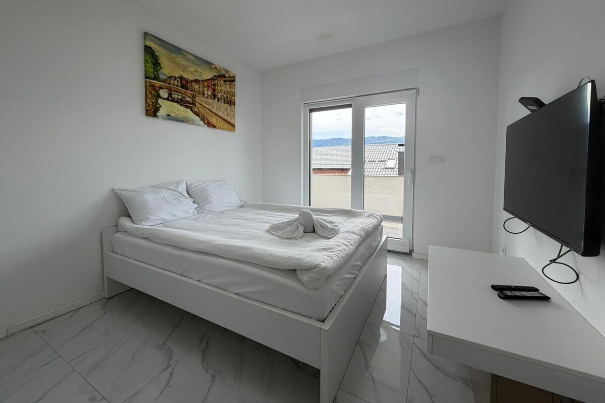 Un dormitorio moderno con una cama, un televisor y un cuadro en la pared.