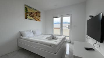 Une chambre à coucher moderne avec un lit, un téléviseur et un tableau accroché au mur.