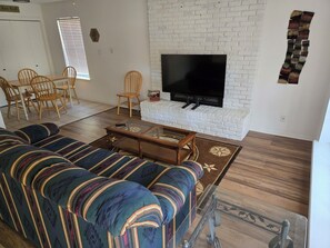 A living room with a sofa, a coffee table, a TV, and a fireplace.