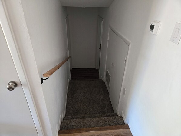 A narrow stairway with a wooden handrail leading to a door at the top.
