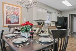 A dining area with a table set for six, a chandelier, and a painting on the wall. - Woodlands 1 Story Retreat • 3BR • Game Room • Gym • Fenced Yard • Dining for 6 (Spring)