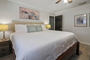 Ein Hotelzimmer mit einem großen Bett, zwei Nachttischen, einem Deckenventilator und Bildern an den Wänden.