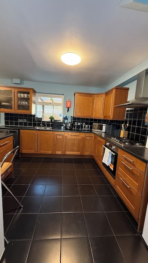 Cozinha moderna com armários de madeira, piso de azulejos pretos e micro-ondas embutido.