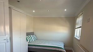 A bedroom with two single beds, a wardrobe, a radiator, and a window with blinds. - Cosy 5-bed house in Swanley (Swanley)