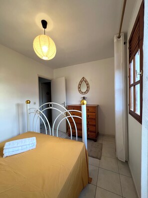A bedroom with a bed, a dresser, a mirror, and a hanging light fixture. - 5 minutes from the beach, spacious family home with beautiful sea views. (Sainte-Anne)