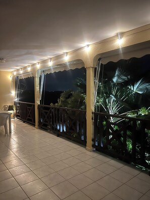 A covered outdoor area with tiled flooring, a railing, and a view of the night sky. - 5 minutes from the beach, spacious family home with beautiful sea views. (Sainte-Anne)