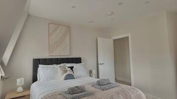A bedroom with a bed, bedside tables, a door, and a ceiling light fixture.