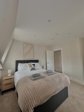A bedroom with a bed, bedside tables, a door, and a ceiling light fixture.