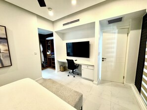 A bedroom with a bed, a desk, a chair, a television, and a wardrobe. - N/H Luxe 2BR/2.5 BA Villa Ocean Views Pool & Gym (Reading)