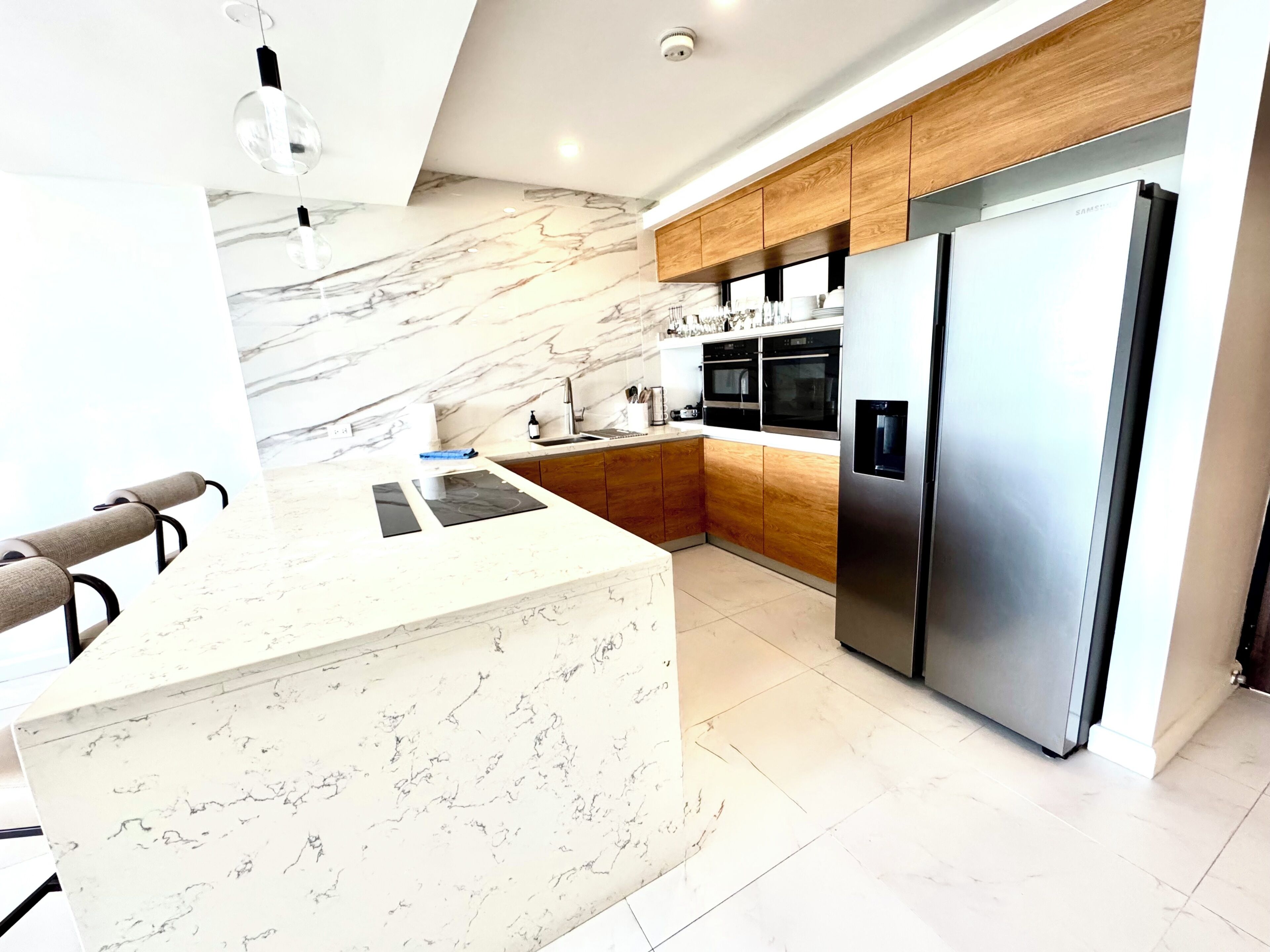A modern kitchen with a marble countertop, stainless steel appliances, and wooden cabinetry.