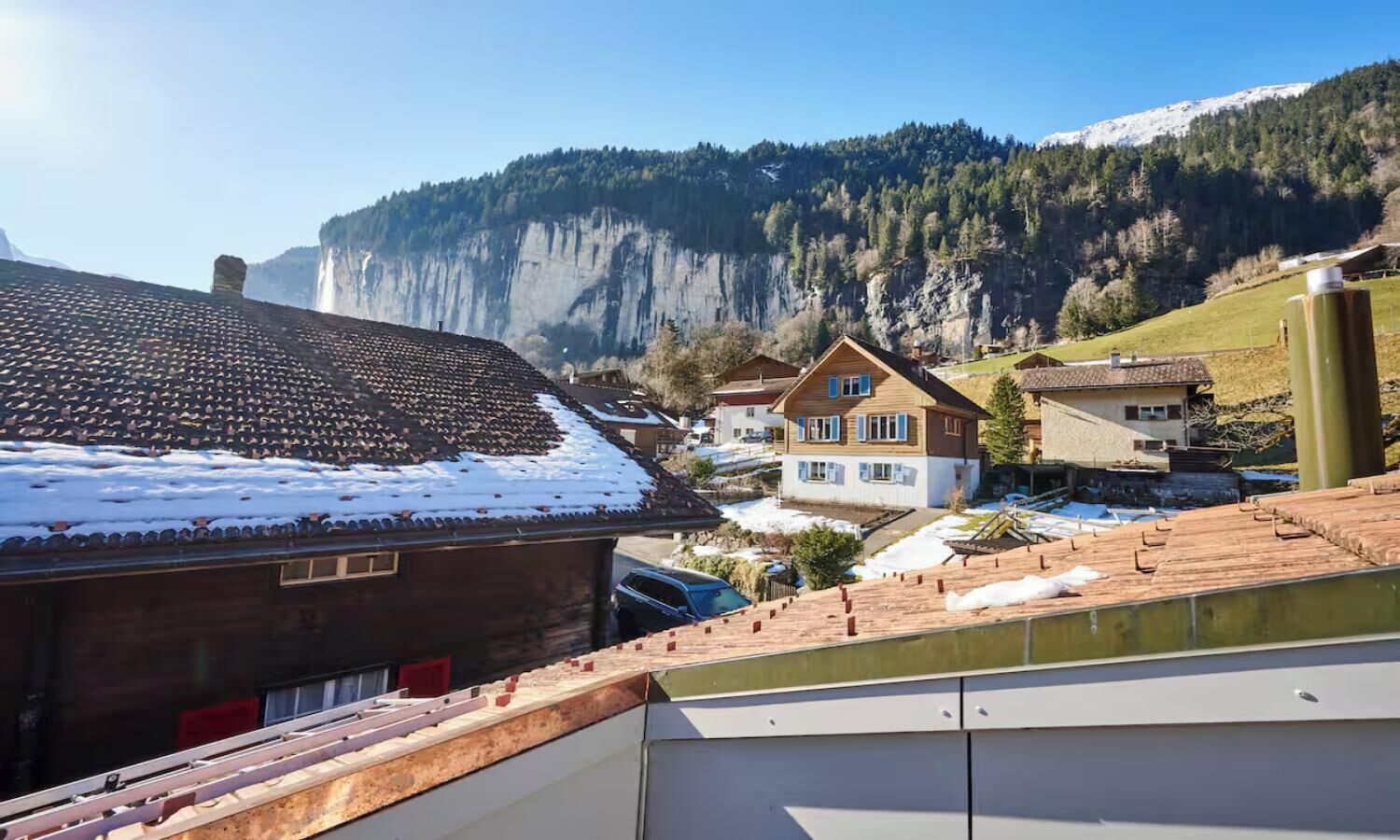 A residential area with houses, a mountain backdrop, and a snowy landscape.