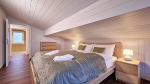 A bedroom with a bed, bedside tables, and a door leading to another room. - CENTRAL 2-BEDROOM APARTMENT IN THE HEART OF LAUTERBRUNNEN (Lauterbrunnen)