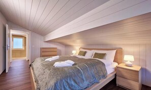 Ein Schlafzimmer mit einem Bett, Nachttischen und einer Tür zu einem anderen Raum.