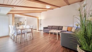 A modern living room with a dining area, wooden flooring, and a grey sofa. - CENTRAL 2-BEDROOM APARTMENT IN THE HEART OF LAUTERBRUNNEN (Lauterbrunnen)