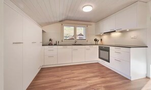 A modern kitchen with white cabinetry, a built-in oven, and a window with a view of the outside. - CENTRAL 2-BEDROOM APARTMENT IN THE HEART OF LAUTERBRUNNEN (Lauterbrunnen)