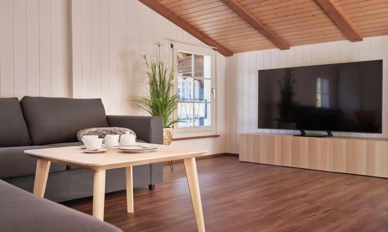 A modern living room with a sofa, a coffee table, and a large flat-screen TV.