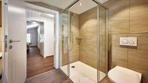 A modern bathroom with a glass shower enclosure, a toilet, and a wall-mounted control panel. - CENTRAL 2-BEDROOM APARTMENT IN THE HEART OF LAUTERBRUNNEN (Lauterbrunnen)