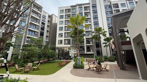 A courtyard with outdoor seating, a pathway, and multi-story residential buildings. - 1BR Pool & WiFi⁠ @ 10 min Patong Beach & Central (Tambon Kathu)