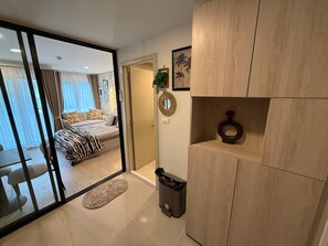 A modern bedroom with a bed, a bedside table, a mirror, and a view through a sliding door to a balcony. - 1BR Pool & WiFi⁠ @ 10 min Patong Beach & Central (Tambon Kathu)