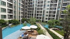 A multi-story residential building with a central swimming pool surrounded by greenery and outdoor seating areas. - 1BR Pool & WiFi⁠ @ 10 min Patong Beach & Central (Tambon Kathu)