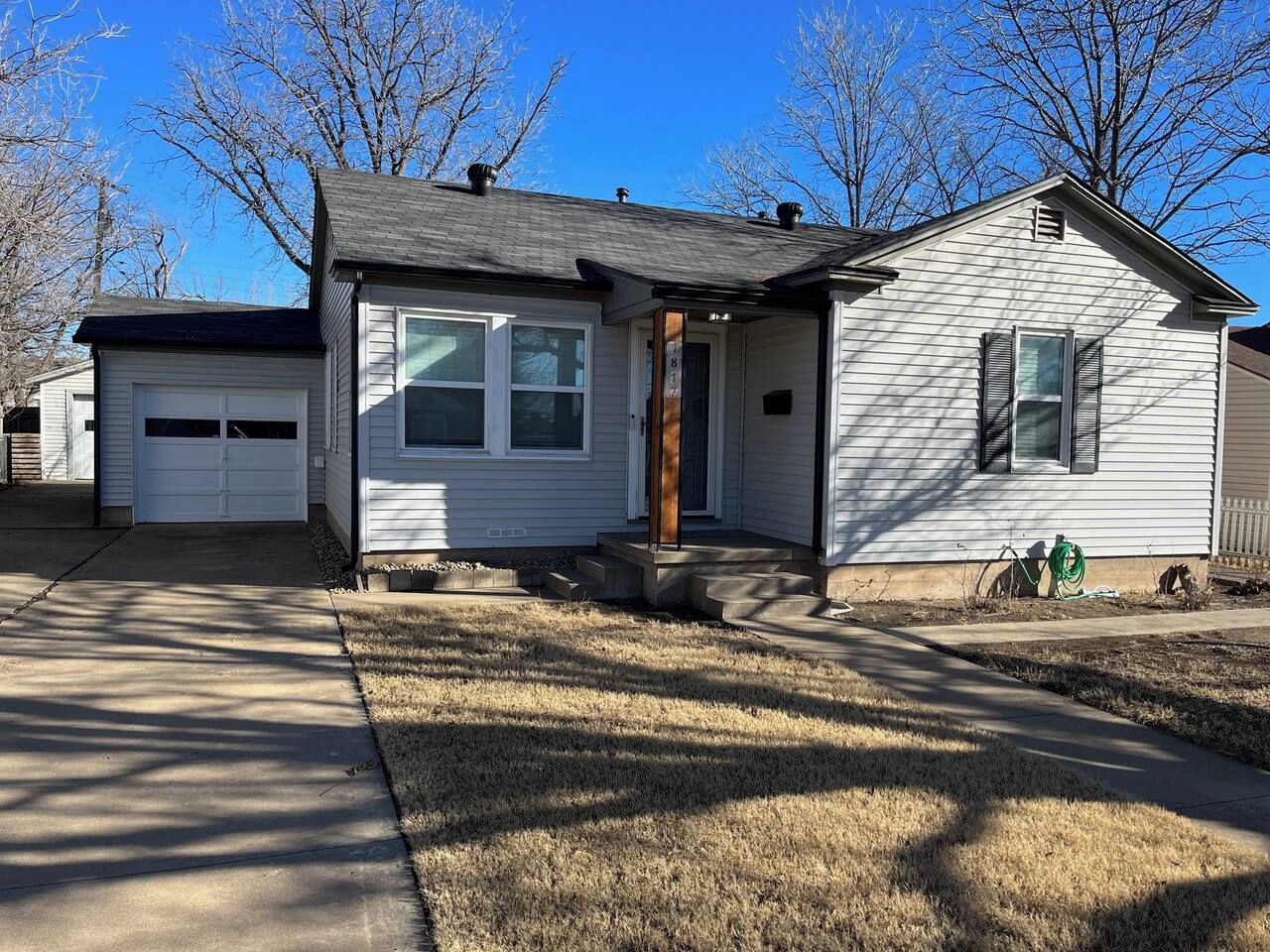A single-story house with a front porch, a garage, and a well-maintained lawn.