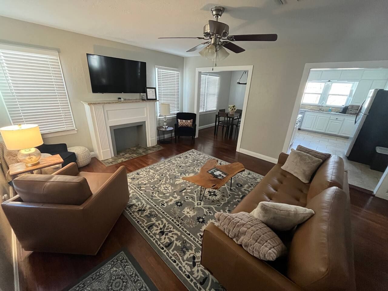 A living room with a fireplace, a television, and a ceiling fan.