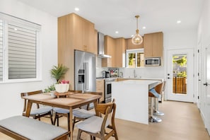 Een moderne keuken met houten kastjes, roestvrijstalen apparatuur en een centraal eiland met barstoelen.