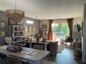 A dining area with a table, chairs, and a chandelier. There is a sofa and a window with curtains. - Starlit Tubac Home , with a Golf Cart! (Tubac)