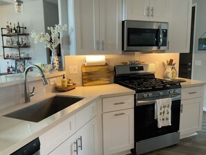 A modern kitchen with a stainless steel stove, a microwave, and a sink. - Starlit Tubac Home , with a Golf Cart! (Tubac)