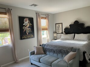 A bedroom with a bed, a sofa, and two windows with curtains. - Starlit Tubac Home , with a Golf Cart! (Tubac)