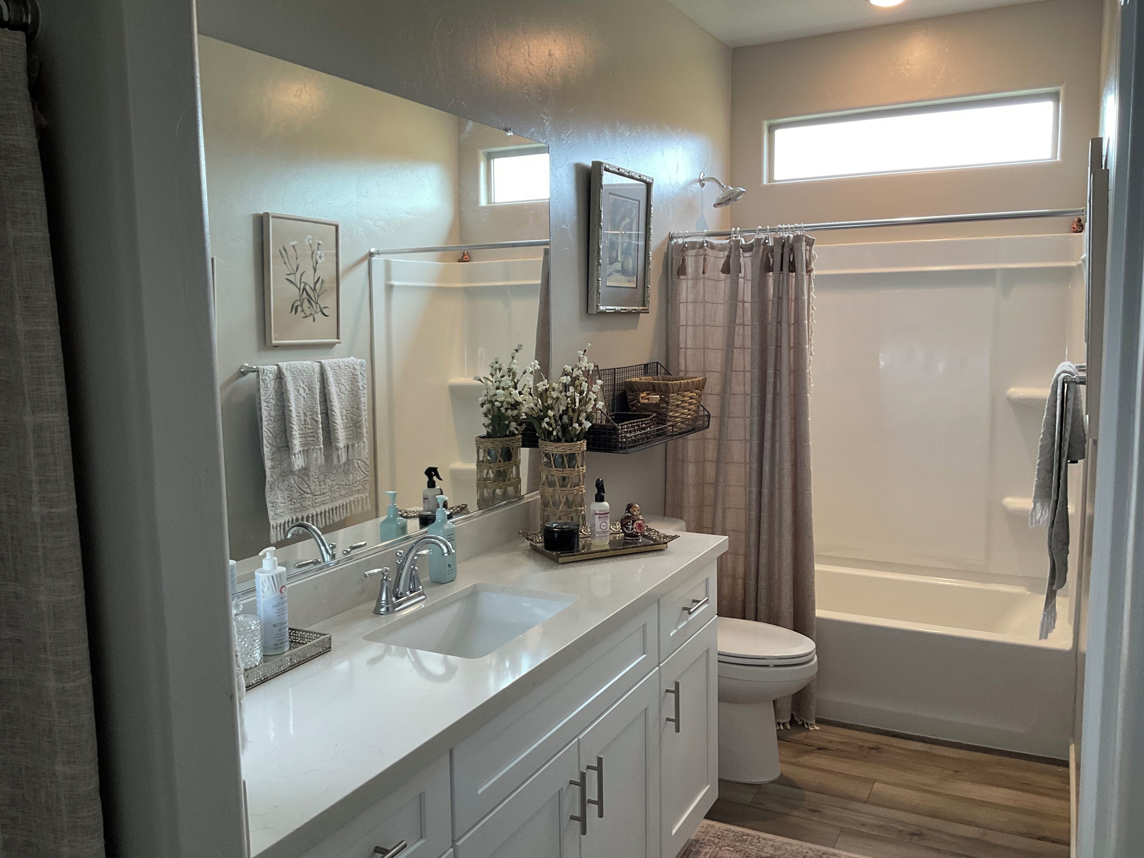 A modern bathroom with a vanity, sink, mirror, toilet, and shower.