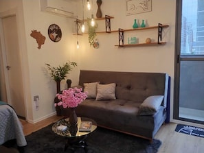 Ein Wohnzimmer mit einer Couch, einem Couchtisch und Dekorationselementen, darunter eine Karte, eine Pflanze und Wandkunst.
