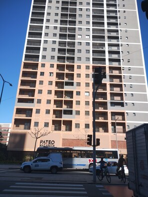 Ein Hochhaus mit mehreren Balkonen und einem Geschäftsbereich im Erdgeschoss.