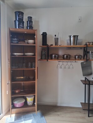 A kitchen with wooden shelves holding various kitchenware, a coffee maker, and a kettle. - Fully equipped studio apartment in Rio with free parking, great location. (Rio de Janeiro)