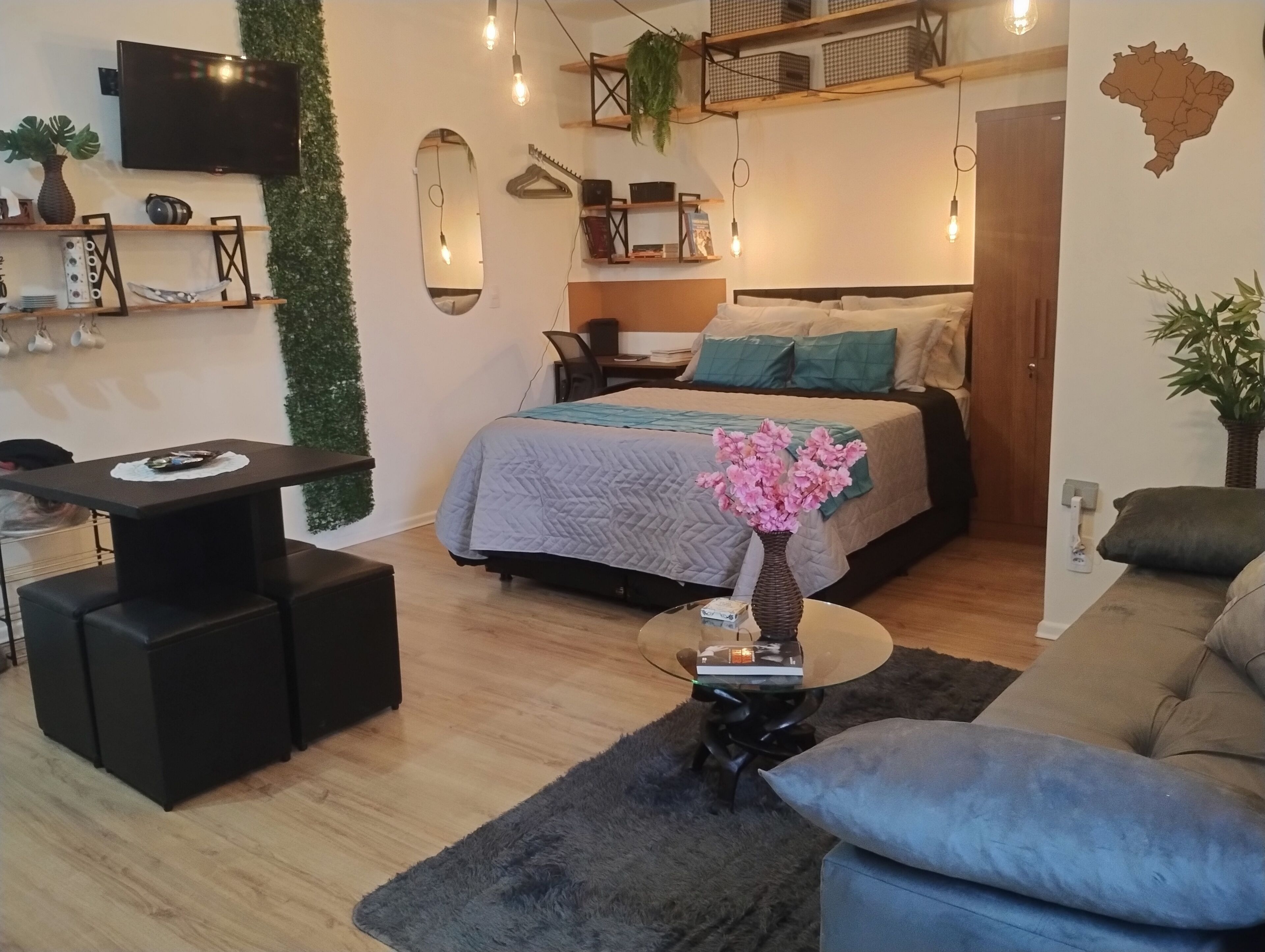 A modern bedroom with a bed, bedside table, and a small round table with a vase.